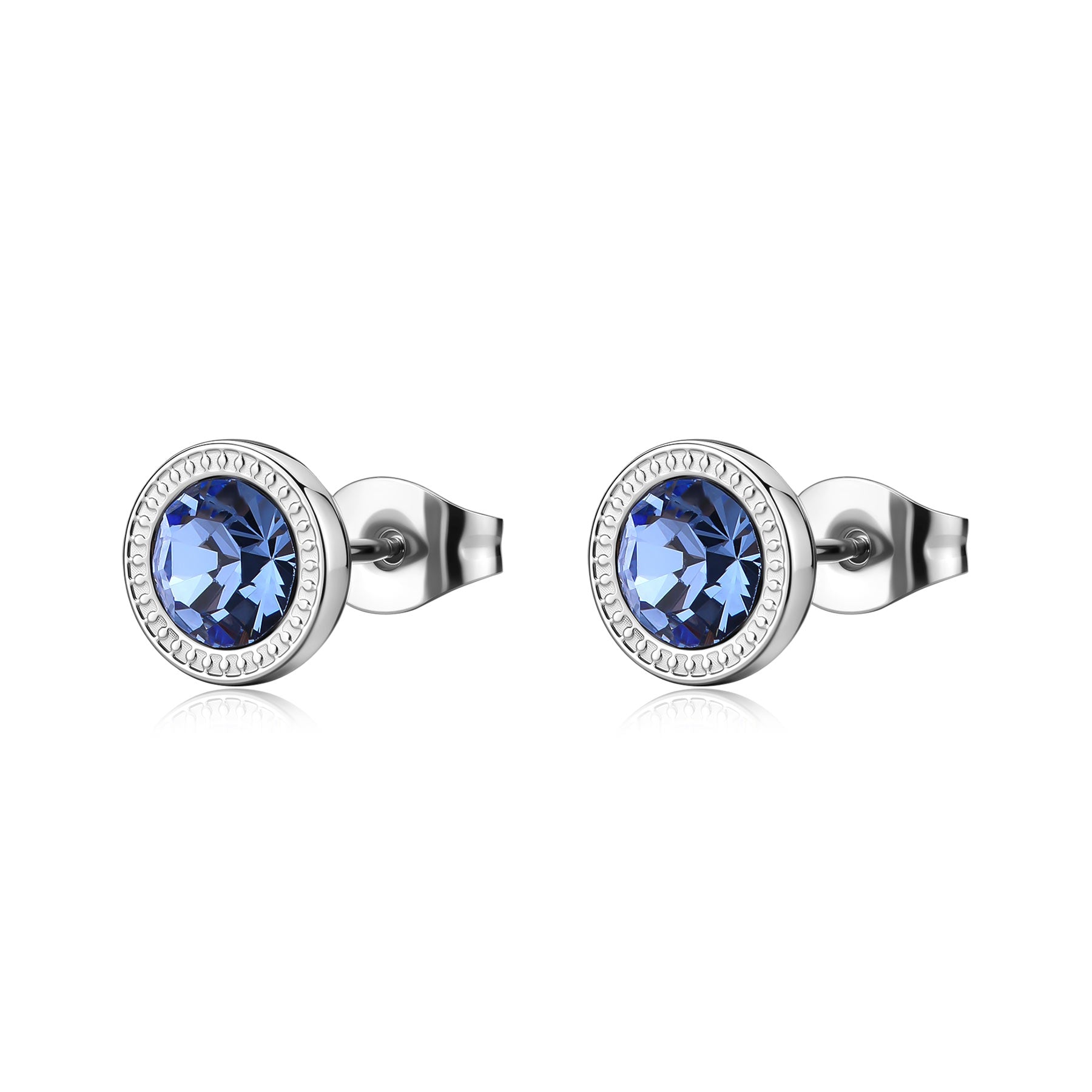 Orecchini a lobo in acciaio 316L lucido con cristallo light sapphire circolare. La pietra è incastonata in una ghiera d'acciaio con bordo finemente lavorato a piccoli intagli geometrici.