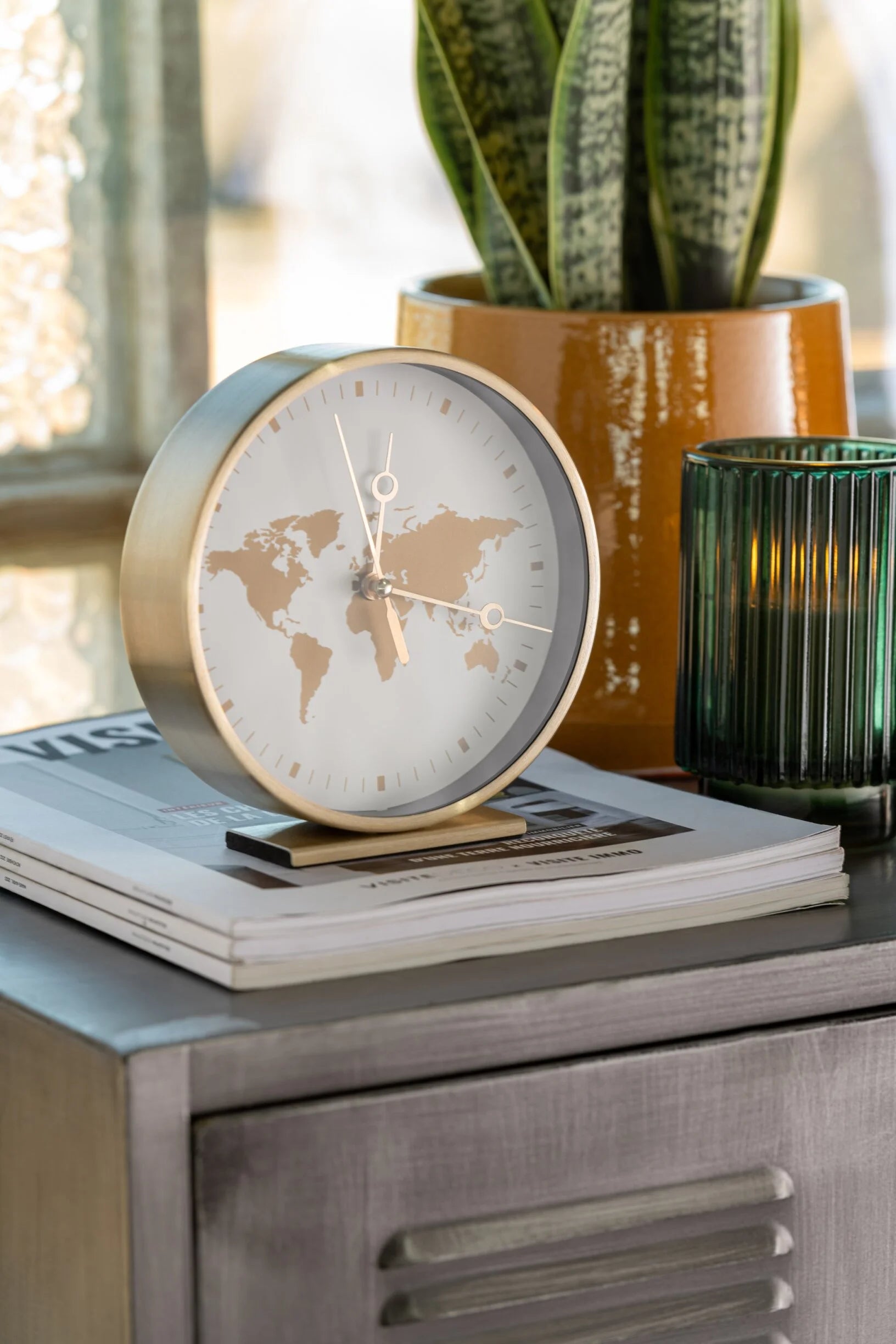 Orologi da tavolo assortiti con struttura in metallo color oro firmati Jolipa, caratterizzati da un elegante quadrante rotondo decorato con un planisfero dorato e lancette sottili abbinate. Disponibili nelle varianti con sfondo nero o bianco, questi orologi decorativi di design su base rettangolare rappresentano un complemento d'arredo moderno e sofisticato ideale per l'ufficio o il soggiorno.