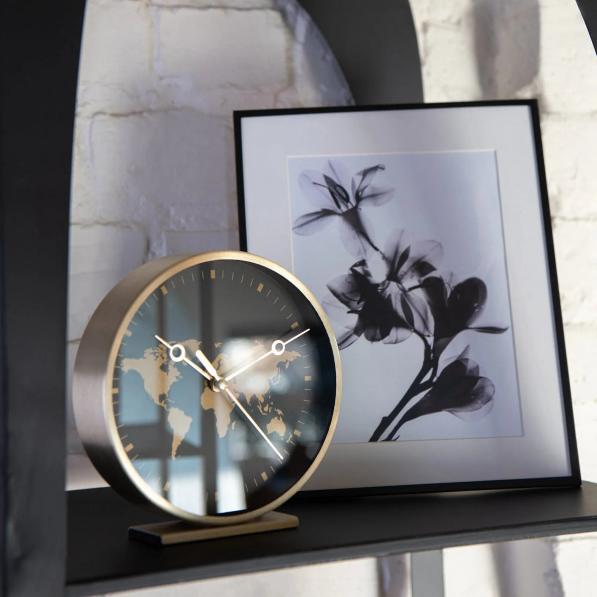 Orologi da tavolo assortiti con struttura in metallo color oro firmati Jolipa, caratterizzati da un elegante quadrante rotondo decorato con un planisfero dorato e lancette sottili abbinate. Disponibili nelle varianti con sfondo nero o bianco, questi orologi decorativi di design su base rettangolare rappresentano un complemento d'arredo moderno e sofisticato ideale per l'ufficio o il soggiorno.