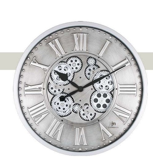 Orologio da parete circolare "Ingranaggi Rotanti Silver" di Justaminute. Il design è caratterizzato da un quadrante in metallo argentato con finitura spazzolata, numeri romani classici a rilievo lungo il bordo e un centro a vista che rivela un complesso meccanismo di ingranaggi neri e grigi. Le lancette nere a goccia contrastano con il fondo metallico, mentre il logo "jm Justaminute" è posizionato in basso a destra.
