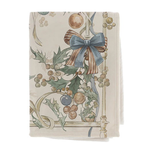 Maxi Plaid Blanc Mariclò Intrecci di Sogni in morbido tessuto panna. Dettaglio della stampa con grande fiocco azzurro a righe, foglie di agrifoglio e palline natalizie nei toni del bronzo e oro.