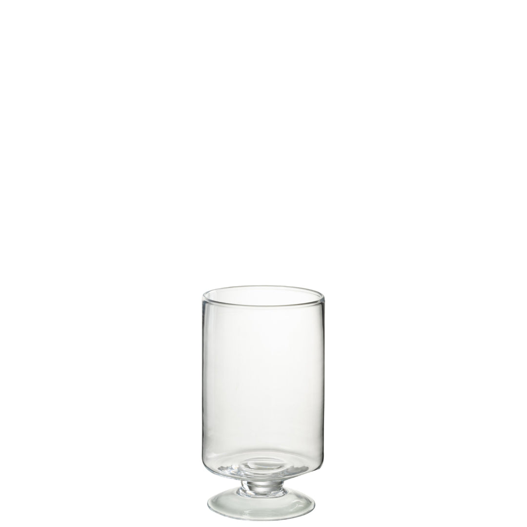 Un portacandela in vetro trasparente, dal design lineare e cilindrico, sostenuto da una piccola base a piede che ne dona stabilità ed eleganza. Le pareti lisce e sottili lasciano trasparire completamente la fiamma, esaltandone la luminosità. Un accessorio dal gusto minimale e raffinato, perfetto come portacandela o lanterna decorativa per la tavola e gli ambienti living.