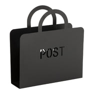 Porta riviste in metallo nero opaco a forma di borsa con doppio manico ad arco, con scritta "POST" traforata sul fronte. Complemento d'arredo funzionale firmato Jolipa, ideale per organizzare riviste, giornali o posta in soggiorno e ingresso.