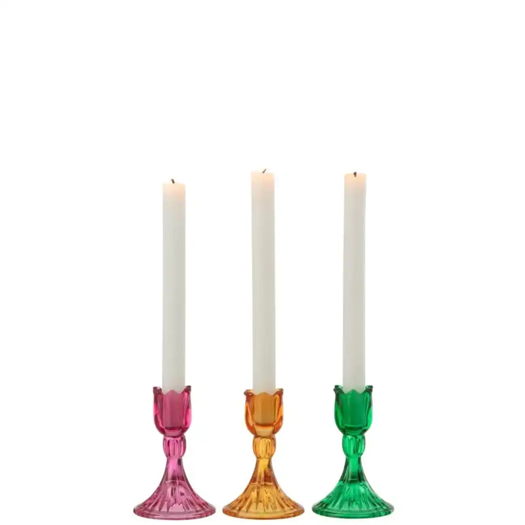 Portacandele alti a forma di bocciolo di tulipano in vetro colorato assortiti firmati Jolipa, caratterizzati da una sommità sagomata a petali e da una base svasata lavorata con eleganti scanalature verticali. Disponibili nelle tre vivaci varianti trasparente rosa, ambra e verde, questi raffinati candelabri decorativi di design sono perfetti per sorreggere candele lunghe a stelo, impreziosire la tavola e donare un tocco di colore ed eleganza all'home decor.