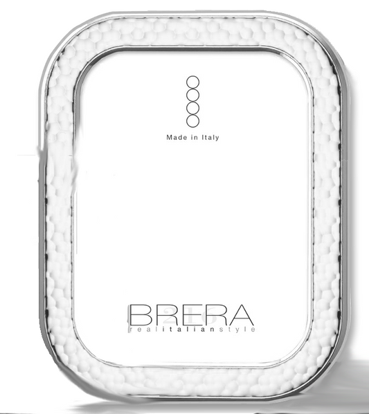 Portafoto da tavolo con cornice rettangolare ad angoli arrotondati in argento bilaminato. La superficie della cornice presenta una lavorazione martellata a rilievo che crea un gioco di luci e ombre. L'interno mostra un inserto bianco con il logo "BRERA real italian style" e la dicitura "Made in Italy".