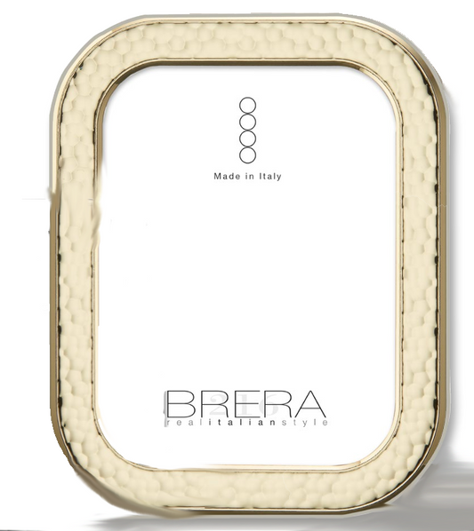 Portafoto da tavolo con cornice rettangolare ad angoli arrotondati in argento placcato oro. La superficie della cornice presenta una lavorazione martellata a rilievo che crea un gioco di luci e ombre. L'interno mostra un inserto bianco con il logo "BRERA real italian style" e la dicitura "Made in Italy".