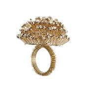 Portatovagliolo ad anello decorato firmato Blanc Mariclo', caratterizzato da una ricca composizione superiore formata da lucide perlinedorate. Questo raffinato accessorio per la tavola di Natale presenta una struttura circolare rivestita da piccoli elementi natalizi coordinati, ideale per impreziosire i tovaglioli di tessuto e creare un'atmosfera festiva e accogliente durante i pranzi e le cene delle festività.