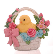 Decorazione pasquale scultorea Vetur in poliresina. Piccolo pulcino giallo seduto all'interno di un cestino intrecciato bianco, circondato da una ricca composizione di rose rosa, fiori azzurri e tulipani, rifinito con un fiocco rosa.