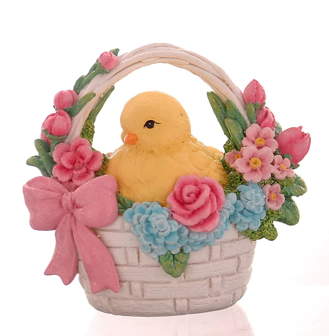 Decorazione pasquale scultorea Vetur in poliresina. Piccolo pulcino giallo seduto all'interno di un cestino intrecciato bianco, circondato da una ricca composizione di rose rosa, fiori azzurri e tulipani, rifinito con un fiocco rosa.