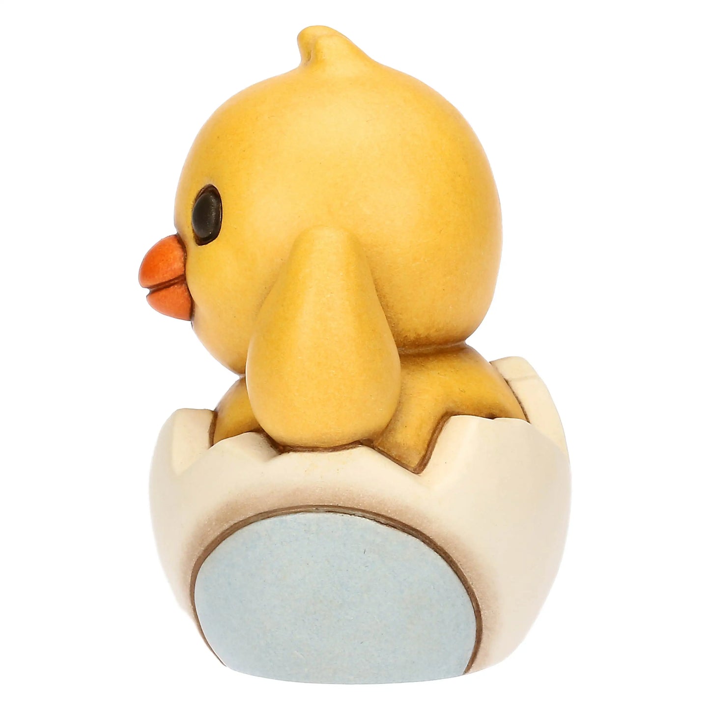 Statuina in ceramica Thun del Pulcino Polly, collezione Incanto di Pasqua. Il pulcino giallo è raffigurato mentre esce da un guscio d'uovo bianco e azzurro, con un'ala alzata in segno di saluto. Decorazione pasquale da collezione con i tipici tratti morbidi e i colori sfumati del marchio Thun.