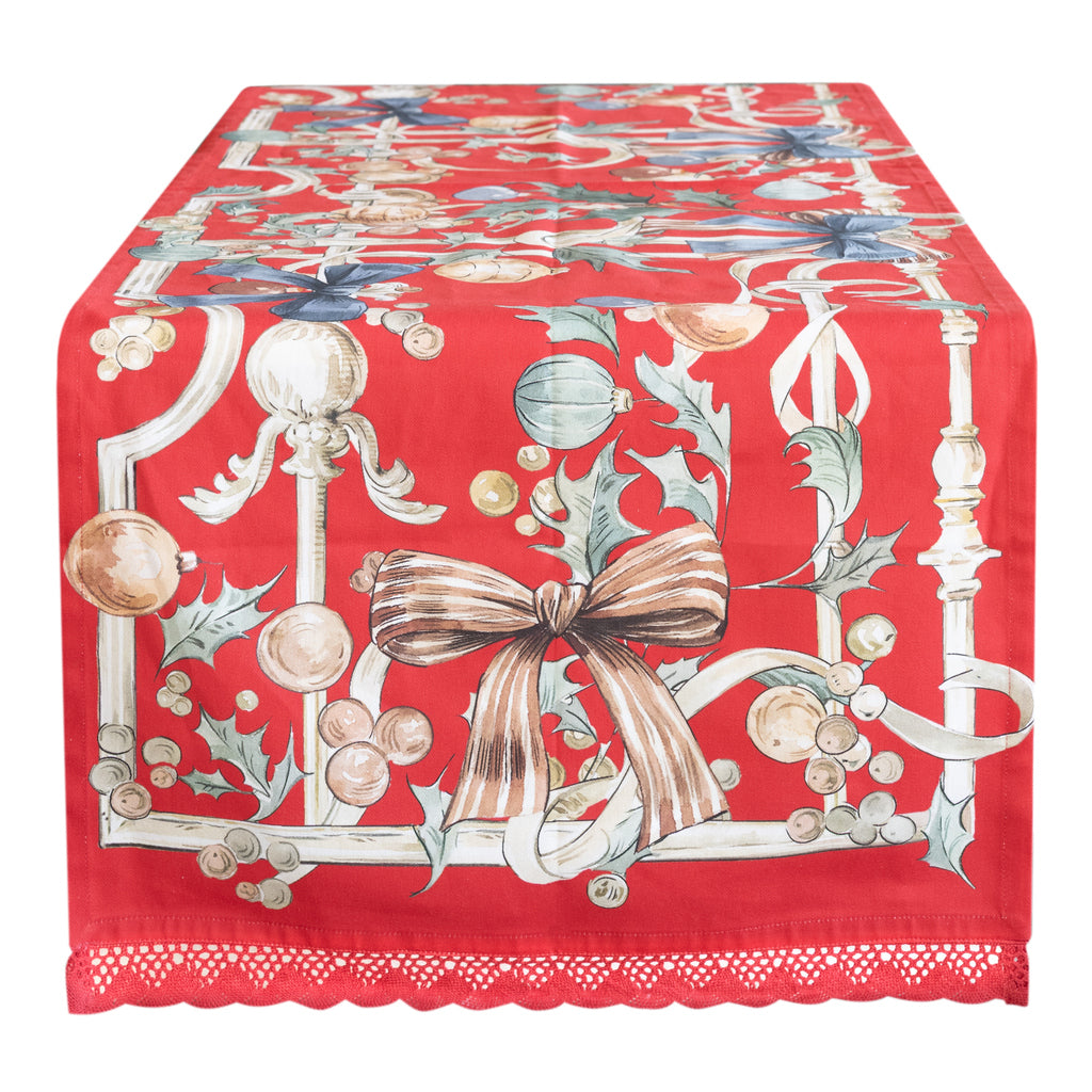 Runner rettangolare in cotone Blanc Mariclò con raffinato bordo in pizzo applicato sui lati. La superficie presenta una stampa natalizia dettagliata su fondo chiaro, ideale per una mise en place in stile shabby chic e romantico.