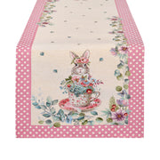 Runner pasquale EDG Enzo de Gasperi con bordo a pois rosa. Decorazione centrale con illustrazioni vintage di coniglietti, tazze da tè fiorite e farfalle. Tessuto elegante per la tavola di Pasqua 2026.