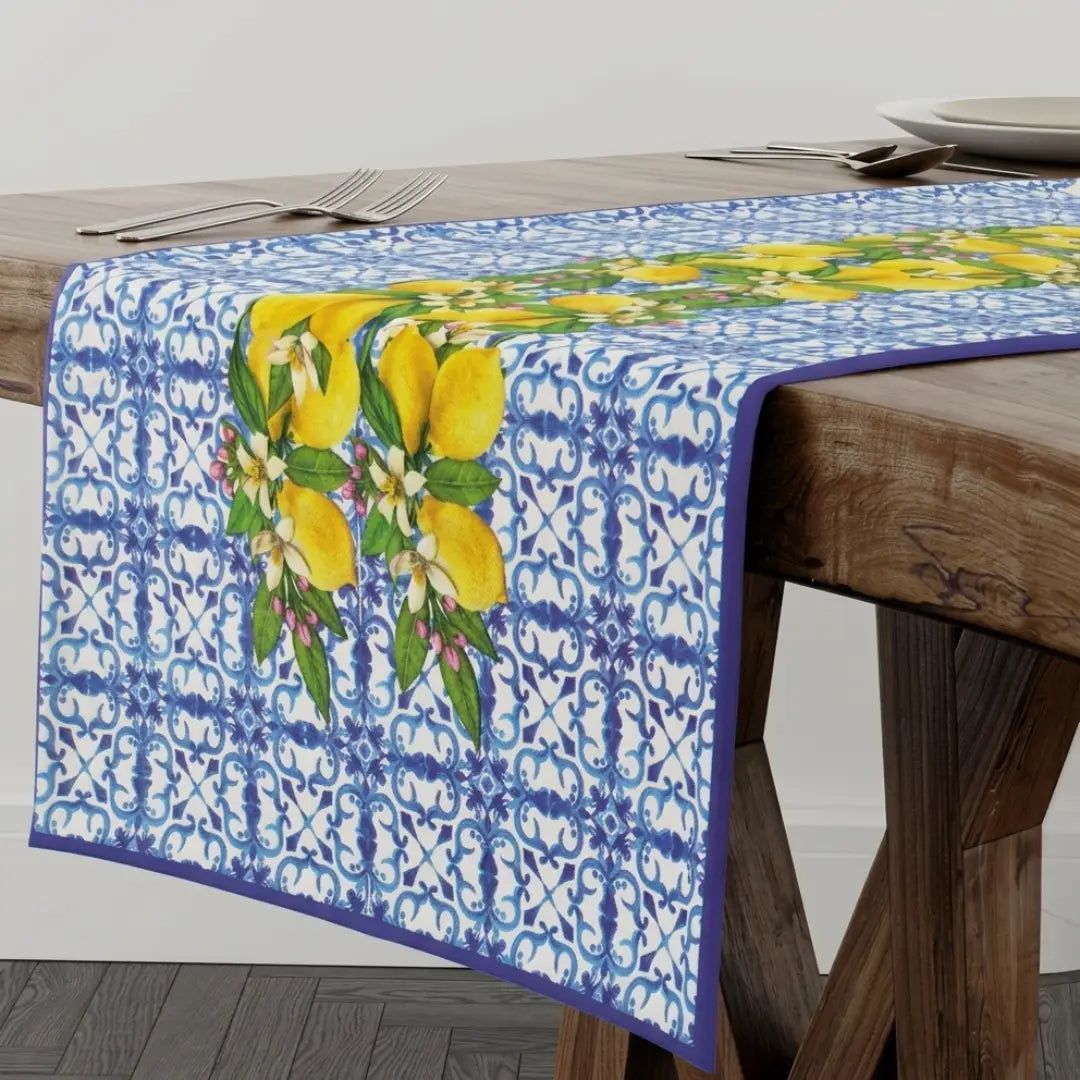 Runner da tavola firmato Gev Casa caratterizzato da una vivace stampa stile maiolica blu con limoni gialli e foglie verdi. Questo elegante runner in stile siciliano è ideale per decorare e valorizzare la tavola da pranzo con un tocco fresco e mediterraneo.