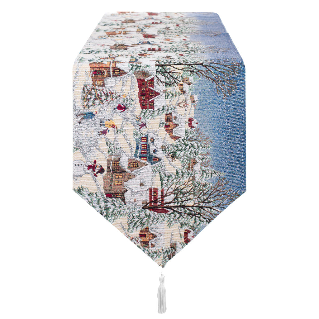 Runner Gobelin Blanc Mariclò Borgo Alpino, 33x170 cm. Tessuto jacquard con paesaggio invernale innevato, casette di montagna e sciatori. Punta a triangolo rifinita con un elegante nappa bianca.