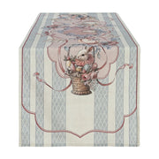 Runner da tavola della linea "Joyeuses Paques" caratterizzato da un'elegante trama a righe verticali beige e azzurre con decorazioni d'ispirazione vintage. Il pannello centrale nei toni del rosa racchiude una raffinata illustrazione pasquale con un coniglietto dentro un cesto intrecciato, uova colorate e rose, ideale per apparecchiare la tavola delle feste in perfetto stile shabby chic.