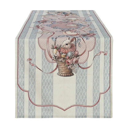 Runner da tavola della linea "Joyeuses Paques" caratterizzato da un'elegante trama a righe verticali beige e azzurre con decorazioni d'ispirazione vintage. Il pannello centrale nei toni del rosa racchiude una raffinata illustrazione pasquale con un coniglietto dentro un cesto intrecciato, uova colorate e rose, ideale per apparecchiare la tavola delle feste in perfetto stile shabby chic.