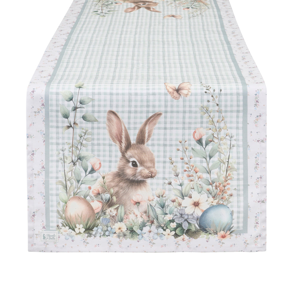 Runner pasquale Nuvole di Stoffa in cotone celeste a quadretti vichy. Decorazione con illustrazioni di coniglietti, uova colorate e fiori delicati. Elegante tessile tavola per Pasqua 2026.