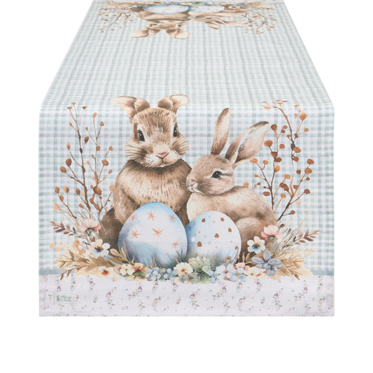 Runner pasquale Nuvole di Stoffa in cotone celeste a quadretti vichy. Decorazione con illustrazioni di coniglietti, uova colorate e fiori delicati. Elegante tessile tavola per Pasqua 2026.