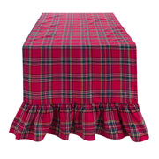 Runner natalizio Blanc Mariclò collezione Magia Tartan. Tessuto a quadri rossi e verdi con elegante gala arricciata sul bordo, steso su un tavolo su sfondo bianco neutro.