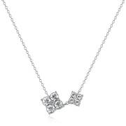 Collana S'Agapõ in acciaio lucido della linea Gleam, composta da una sottile catenina e un pendente asimmetrico formato da due fiori stilizzati di diverse dimensioni, entrambi impreziositi da quattro cristalli bianchi circolari.