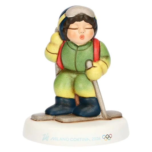 Statuina in ceramica THUN di uno sciatore di fondo per Milano Cortina 2026. Atleta con tuta verde, sci e bastoncini su base con loghi olimpici.