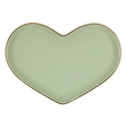 Un vassoio in ceramica a forma di cuore, fotografato dall'alto su uno sfondo bianco uniforme. Il vassoio presenta una superficie liscia e piatta di un delicato color verde salvia opaco. Il bordo è leggermente rialzato e rifinito con un sottile profilo dorato lucido che ne delinea l'intera silhouette, aggiungendo un tocco elegante e prezioso. La forma del cuore è simmetrica, con linee morbide e arrotondate, progettata per ospitare comodamente le due tazze coordinate della stessa collezione.