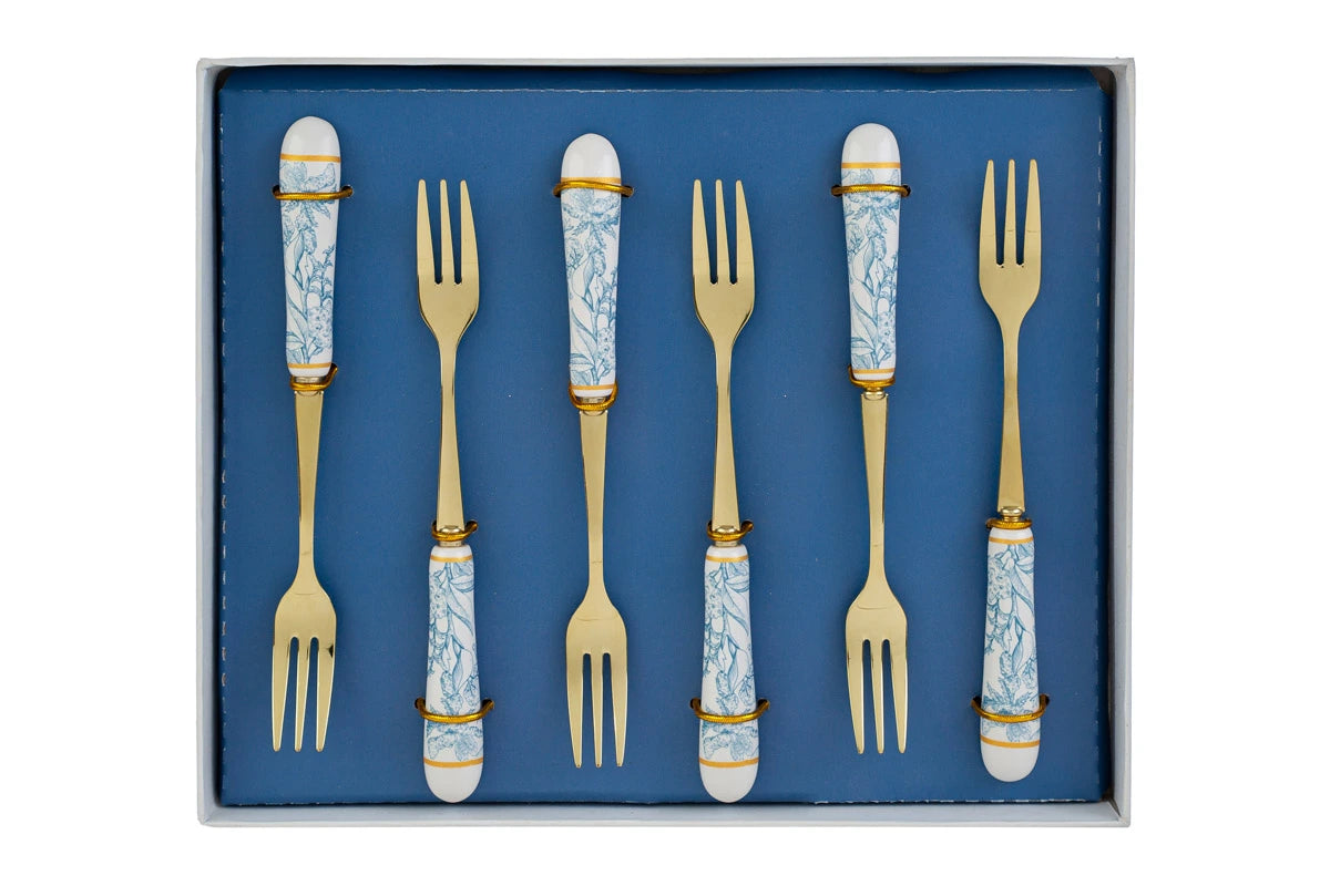 Set di 6 forchettine da dolce con decoro azzurro firmato Le Stelle, caratterizzato da rebbi in metallo color oro e raffinati manici in porcellana bianca decorati con delicati motivi floreali azzurri. Questo elegante servizio di posate da dessert di design è accompagnato dalla sua scatola regalo quadrata coordinata con la stessa fantasia botanica, perfetto come bomboniera di classe o idea regalo home decor.