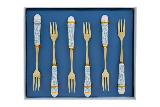 Set di 6 forchettine da dolce con decoro azzurro firmato Le Stelle, caratterizzato da rebbi in metallo color oro e raffinati manici in porcellana bianca decorati con delicati motivi floreali azzurri. Questo elegante servizio di posate da dessert di design è accompagnato dalla sua scatola regalo quadrata coordinata con la stessa fantasia botanica, perfetto come bomboniera di classe o idea regalo home decor.