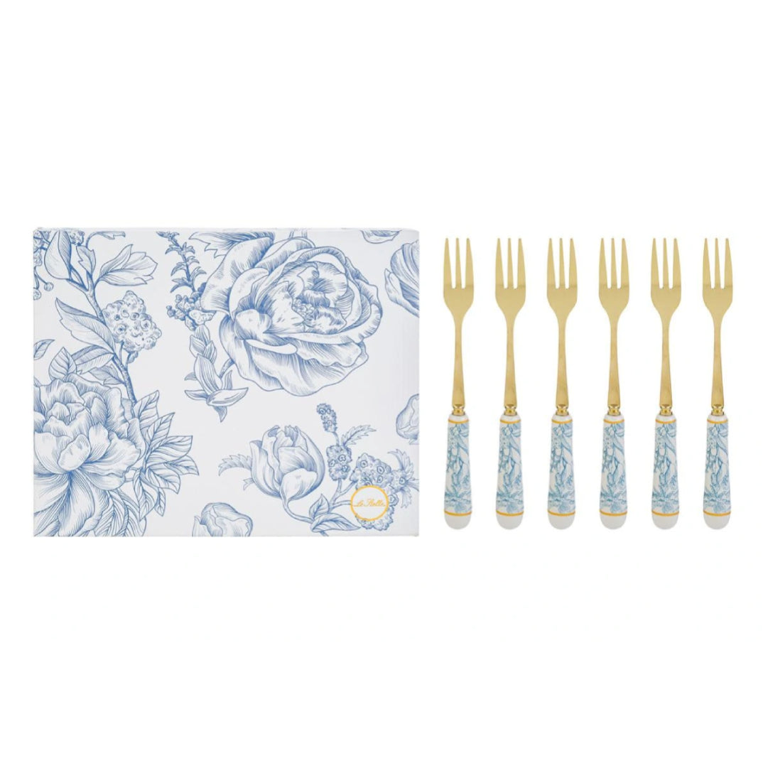 Set di 6 forchettine da dolce con decoro azzurro firmato Le Stelle, caratterizzato da rebbi in metallo color oro e raffinati manici in porcellana bianca decorati con delicati motivi floreali azzurri. Questo elegante servizio di posate da dessert di design è accompagnato dalla sua scatola regalo quadrata coordinata con la stessa fantasia botanica, perfetto come bomboniera di classe o idea regalo home decor.