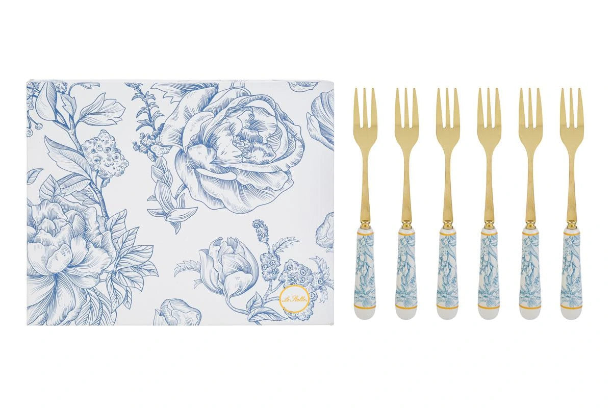 Set di 6 forchettine da dolce con decoro azzurro firmato Le Stelle, caratterizzato da rebbi in metallo color oro e raffinati manici in porcellana bianca decorati con delicati motivi floreali azzurri. Questo elegante servizio di posate da dessert di design è accompagnato dalla sua scatola regalo quadrata coordinata con la stessa fantasia botanica, perfetto come bomboniera di classe o idea regalo home decor.