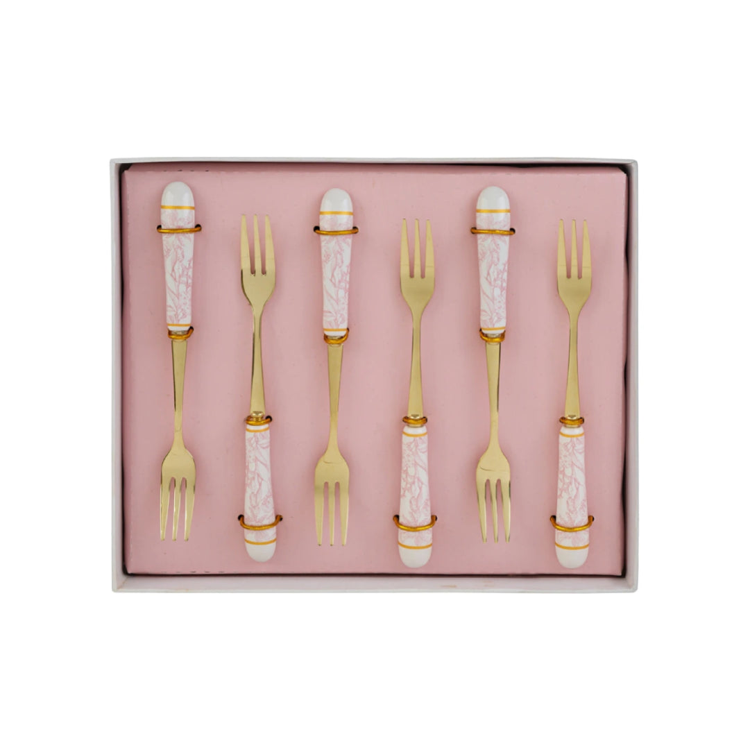 Set di 6 forchettine da dolce con decoro rosa firmato Le Stelle, caratterizzato da rebbi in metallo color oro e raffinati manici in porcellana bianca decorati con delicati motivi floreali rosa. Questo elegante servizio di posate da dessert di design è accompagnato dalla sua scatola regalo quadrata coordinata con la stessa fantasia botanica, perfetto come bomboniera di classe o idea regalo home decor.