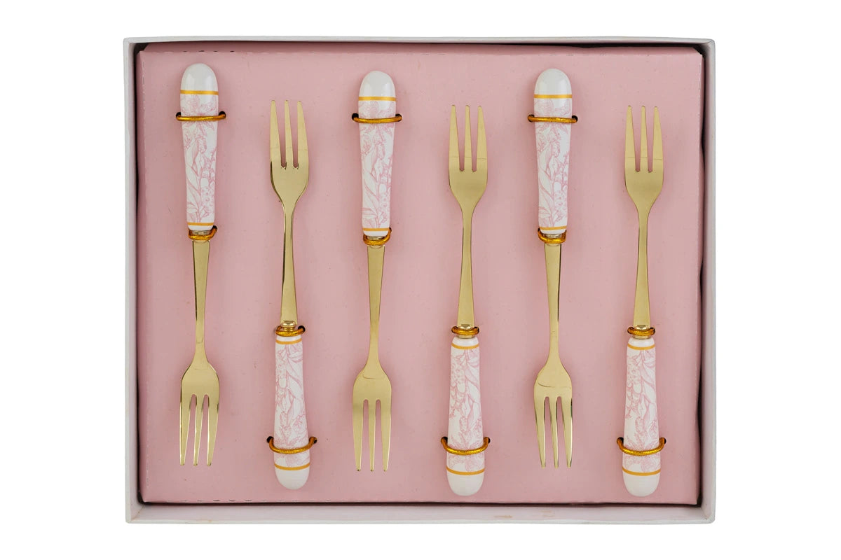 Set di 6 forchettine da dolce con decoro rosa firmato Le Stelle, caratterizzato da rebbi in metallo color oro e raffinati manici in porcellana bianca decorati con delicati motivi floreali rosa. Questo elegante servizio di posate da dessert di design è accompagnato dalla sua scatola regalo quadrata coordinata con la stessa fantasia botanica, perfetto come bomboniera di classe o idea regalo home decor.