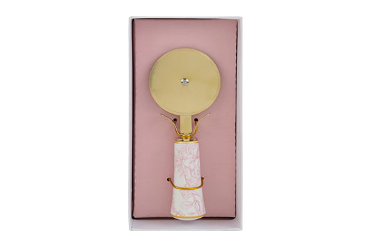 Tagliapizza con decoro rosa firmato Le Stelle, caratterizzato da una lama rotante circolare in metallo color oro e un elegante manico in porcellana bianca decorato con delicati motivi floreali rosati. Questo raffinato utensile da cucina di design è accompagnato dalla sua custodia regalo rettangolare coordinata con la stessa fantasia botanica, perfetto come bomboniera di classe o idea regalo home decor.