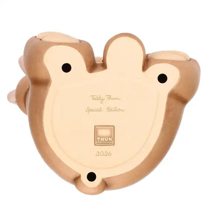Statuina maxi in ceramica dipinta a mano raffigurante il classico orsetto Teddy di Thun. L'orso è seduto in posa sorridente con un occhio chiuso in un occhiolino, indossa un fazzoletto verde al collo e tiene una farfalla rosa e arancione appoggiata sull'orecchio destro sollevato. Design caratterizzato dalle tipiche forme morbide e dai colori caldi del brand.