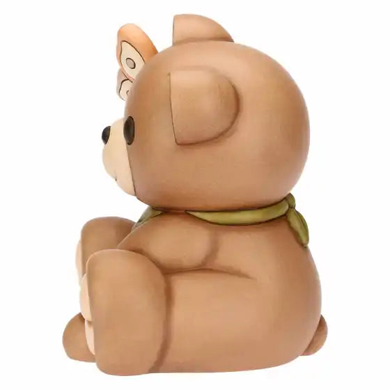 Statuina maxi in ceramica dipinta a mano raffigurante il classico orsetto Teddy di Thun. L'orso è seduto in posa sorridente con un occhio chiuso in un occhiolino, indossa un fazzoletto verde al collo e tiene una farfalla rosa e arancione appoggiata sull'orecchio destro sollevato. Design caratterizzato dalle tipiche forme morbide e dai colori caldi del brand.