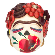 Scultura decorativa in ceramica Thun raffigurante la testa di Frida Kahlo in stile "calavera", caratterizzata da occhi chiusi con ciglia colorate, l'iconico sopracciglio unico e un grande papavero rosso dipinto sul volto. Questa creazione artistica è riccamente adornata da fiori rossi e bordeaux tra i capelli castani, rappresentando un pezzo da collezione unico che celebra l'estetica e la forza della celebre pittrice messicana.