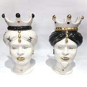 Coppia di Teste di Moro in ceramica bianca lucida con turbanti neri e bianchi decorati da loghi fashion neri e dorati, completate da corone regali e labbra con finitura in oro zecchino. Queste sculture ornamentali di design pop art fondono la tradizione ceramica siciliana con l'estetica del lusso moderno, rappresentando un complemento d'arredo audace ed esclusivo per interni ricercati.