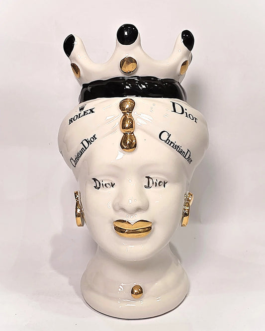 Coppia di Teste di Moro in ceramica bianca lucida con turbanti neri e bianchi decorati da loghi fashion neri e dorati, completate da corone regali e labbra con finitura in oro zecchino. Queste sculture ornamentali di design pop art fondono la tradizione ceramica siciliana con l'estetica del lusso moderno, rappresentando un complemento d'arredo audace ed esclusivo per interni ricercati.