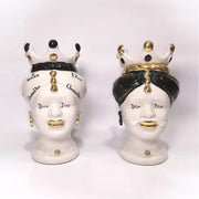 Coppia di Teste di Moro in ceramica bianca lucida con turbanti neri e bianchi decorati da loghi fashion neri e dorati, completate da corone regali e labbra con finitura in oro zecchino. Queste sculture ornamentali di design pop art fondono la tradizione ceramica siciliana con l'estetica del lusso moderno, rappresentando un complemento d'arredo audace ed esclusivo per interni ricercati.