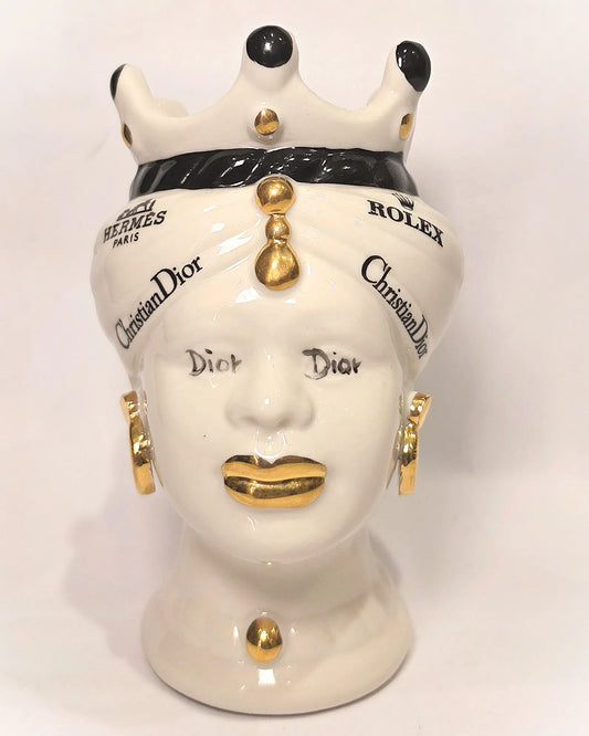 Coppia di Teste di Moro in ceramica bianca lucida con turbanti neri e bianchi decorati da loghi fashion neri e dorati, completate da corone regali e labbra con finitura in oro zecchino. Queste sculture ornamentali di design pop art fondono la tradizione ceramica siciliana con l'estetica del lusso moderno, rappresentando un complemento d'arredo audace ed esclusivo per interni ricercati.