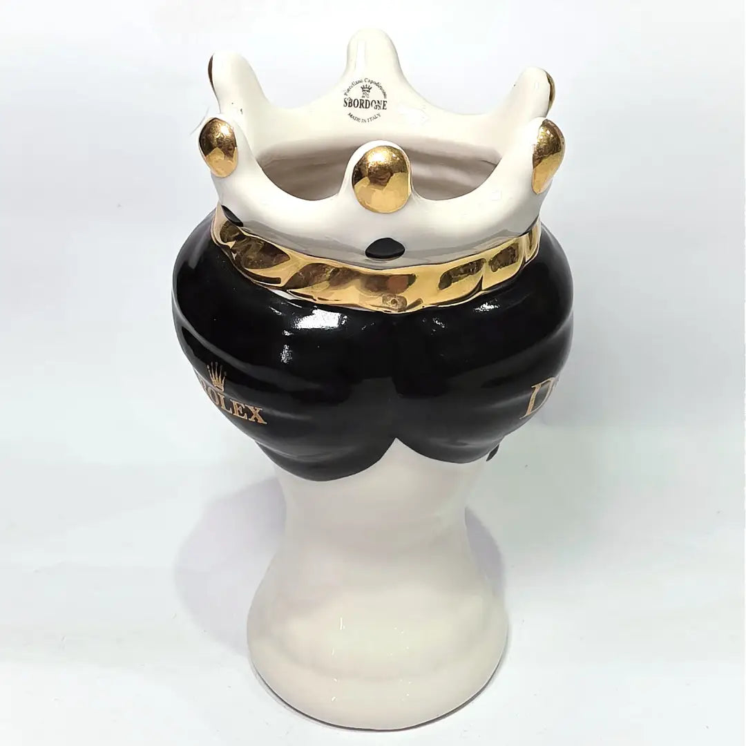 Coppia di Teste di Moro in ceramica bianca lucida con turbanti neri e bianchi decorati da loghi fashion neri e dorati, completate da corone regali e labbra con finitura in oro zecchino. Queste sculture ornamentali di design pop art fondono la tradizione ceramica siciliana con l'estetica del lusso moderno, rappresentando un complemento d'arredo audace ed esclusivo per interni ricercati.