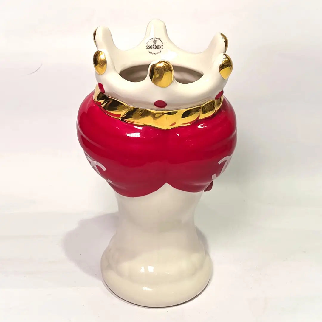 Coppia di Teste di Moro in ceramica bianca lucida con turbanti rosso ciliegia decorati da loghi fashion bianchi, completate da corone regali e labbra con finitura in oro zecchino. Queste sculture ornamentali di design pop art fondono la tradizione ceramica siciliana con l'estetica del lusso moderno, rappresentando un complemento d'arredo audace ed esclusivo per interni ricercati.