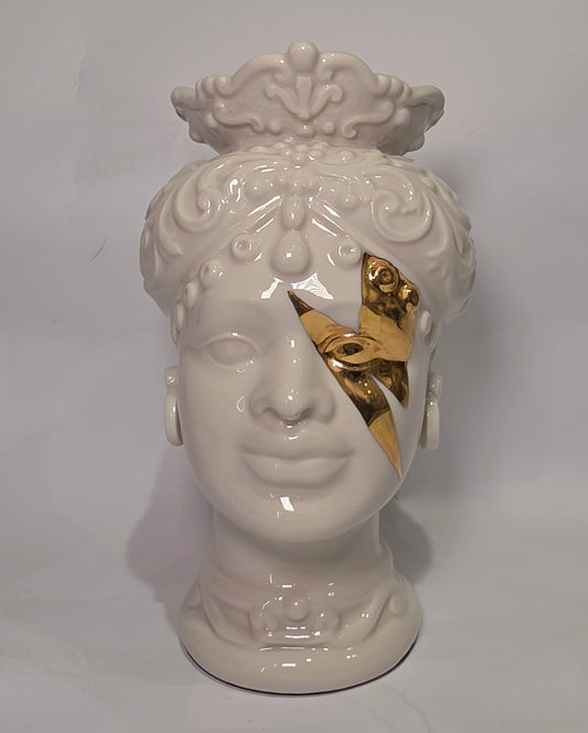 Coppia di Teste di Moro in ceramica artigianale, una in bianco lucido e una in nero lucido, entrambe caratterizzate da un'originale saetta dorata dipinta sul volto. Queste sculture ornamentali dal design pop e contemporaneo fondono la tradizione siciliana con uno stile d'avanguardia, rappresentando un complemento d'arredo iconico ed elegante per interni di lusso.