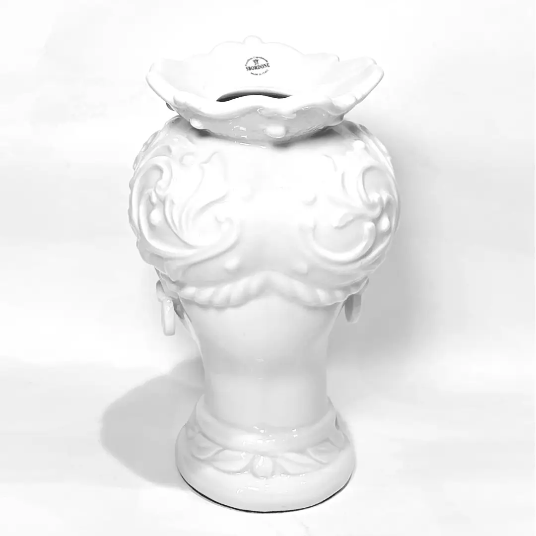 Coppia di Teste di Moro in ceramica artigianale, una in bianco lucido e una in nero lucido, entrambe caratterizzate da un'originale saetta dorata dipinta sul volto. Queste sculture ornamentali dal design pop e contemporaneo fondono la tradizione siciliana con uno stile d'avanguardia, rappresentando un complemento d'arredo iconico ed elegante per interni di lusso.