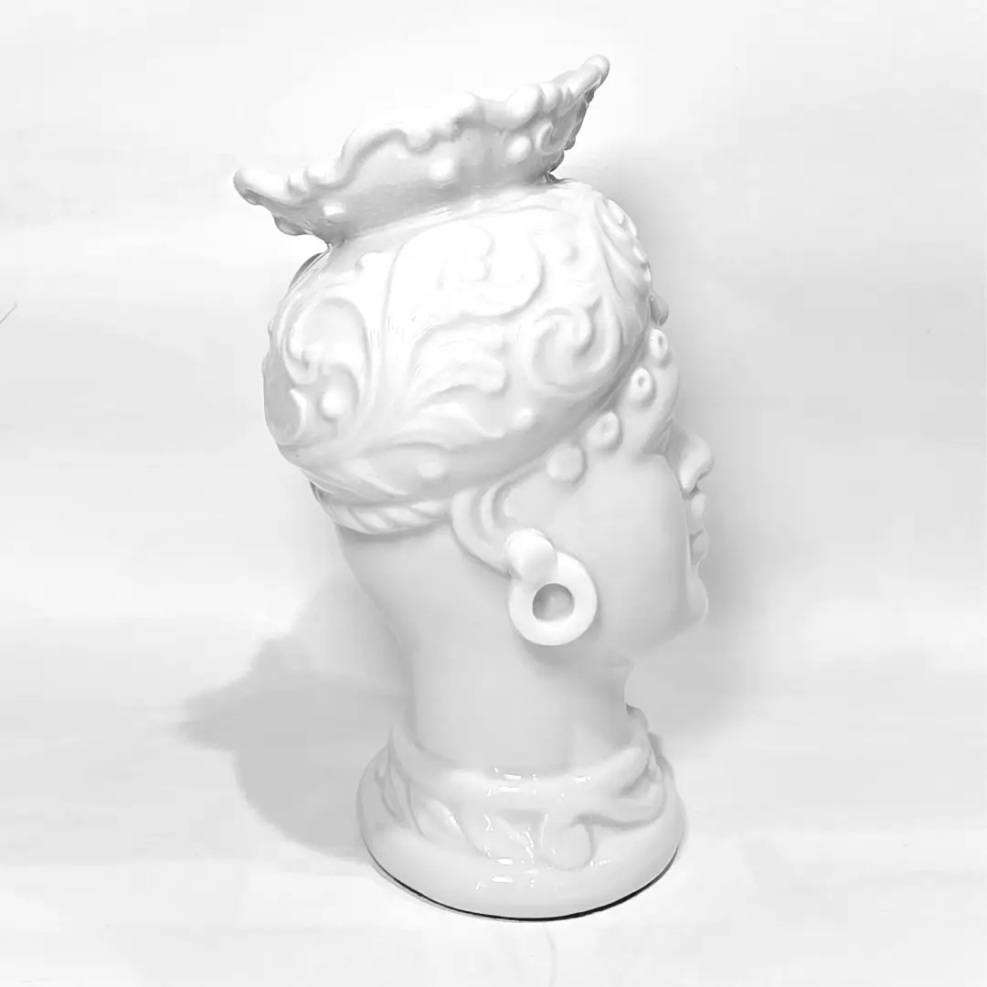 Coppia di Teste di Moro in ceramica artigianale, una in bianco lucido e una in nero lucido, entrambe caratterizzate da un'originale saetta dorata dipinta sul volto. Queste sculture ornamentali dal design pop e contemporaneo fondono la tradizione siciliana con uno stile d'avanguardia, rappresentando un complemento d'arredo iconico ed elegante per interni di lusso.