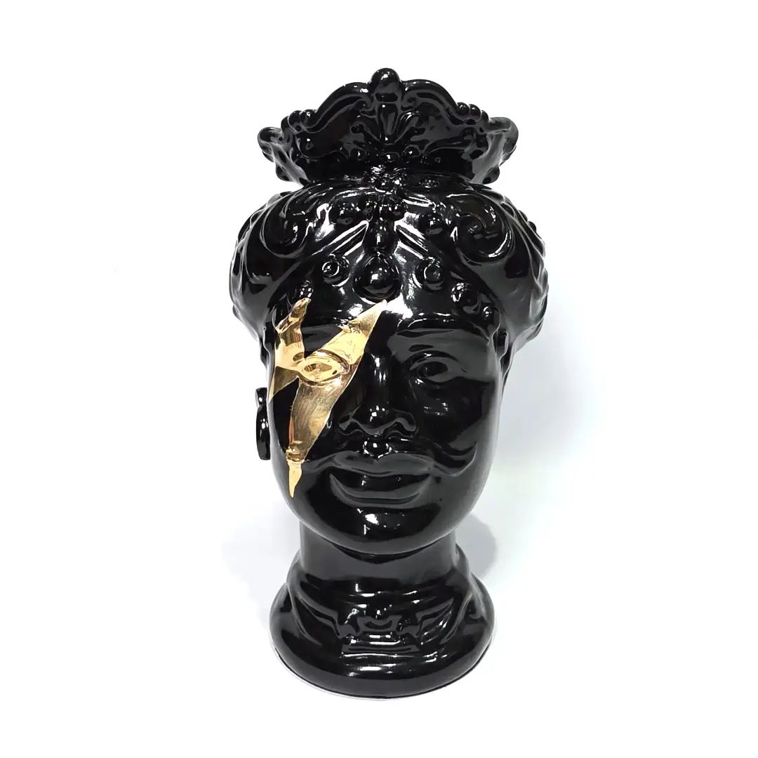 Coppia di Teste di Moro in ceramica artigianale, una in bianco lucido e una in nero lucido, entrambe caratterizzate da un'originale saetta dorata dipinta sul volto. Queste sculture ornamentali dal design pop e contemporaneo fondono la tradizione siciliana con uno stile d'avanguardia, rappresentando un complemento d'arredo iconico ed elegante per interni di lusso.