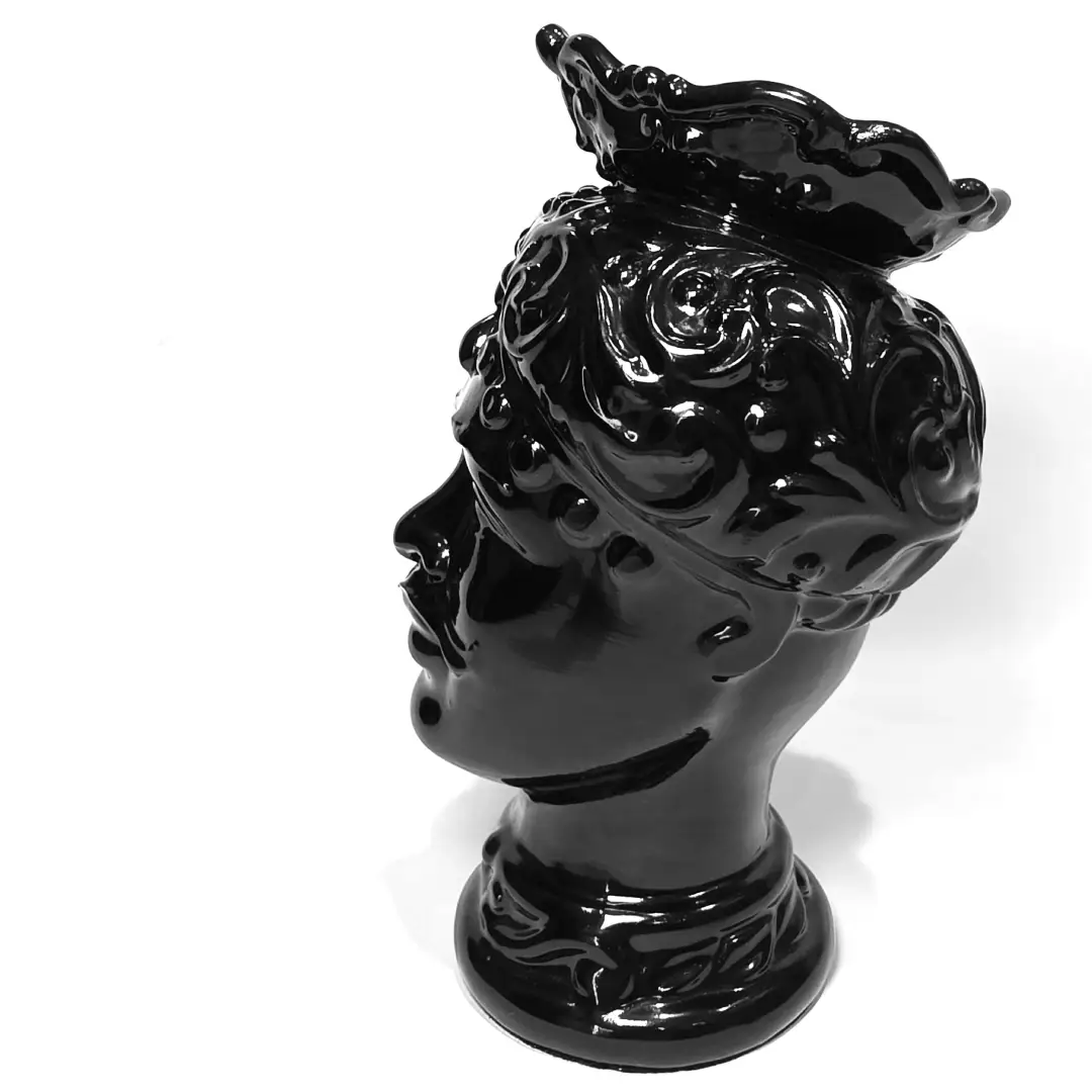 Coppia di Teste di Moro in ceramica artigianale, una in bianco lucido e una in nero lucido, entrambe caratterizzate da un'originale saetta dorata dipinta sul volto. Queste sculture ornamentali dal design pop e contemporaneo fondono la tradizione siciliana con uno stile d'avanguardia, rappresentando un complemento d'arredo iconico ed elegante per interni di lusso.
