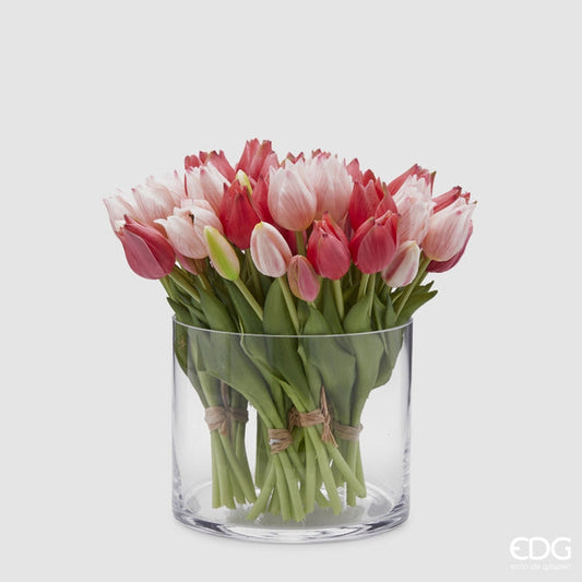 Un ricco bouquet di tulipani in silicone fucsia e rosa mescolati all'interno di un vaso di vetro cilindrico trasparente.