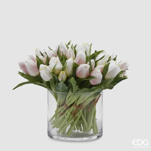 Un ricco bouquet di tulipani in silicone bianchi e rosa mescolati all'interno di un vaso di vetro cilindrico trasparente.