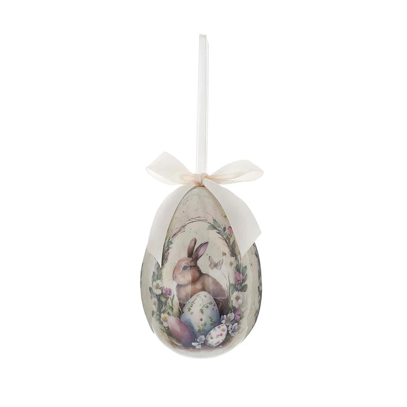 Decorazione pasquale Blanc Mariclò a forma di uovo color crema con fiocco avorio. Il decoro mostra un coniglietto tra uova colorate e ghirlande di fiori campestri.